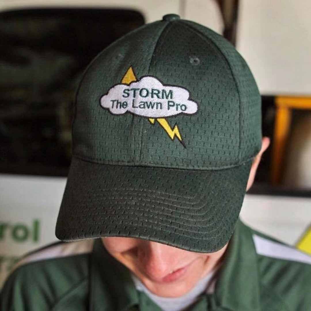 A green hat with a patch of the logo of the Storm - The Lawn Pro of The Fox Cities LLC.