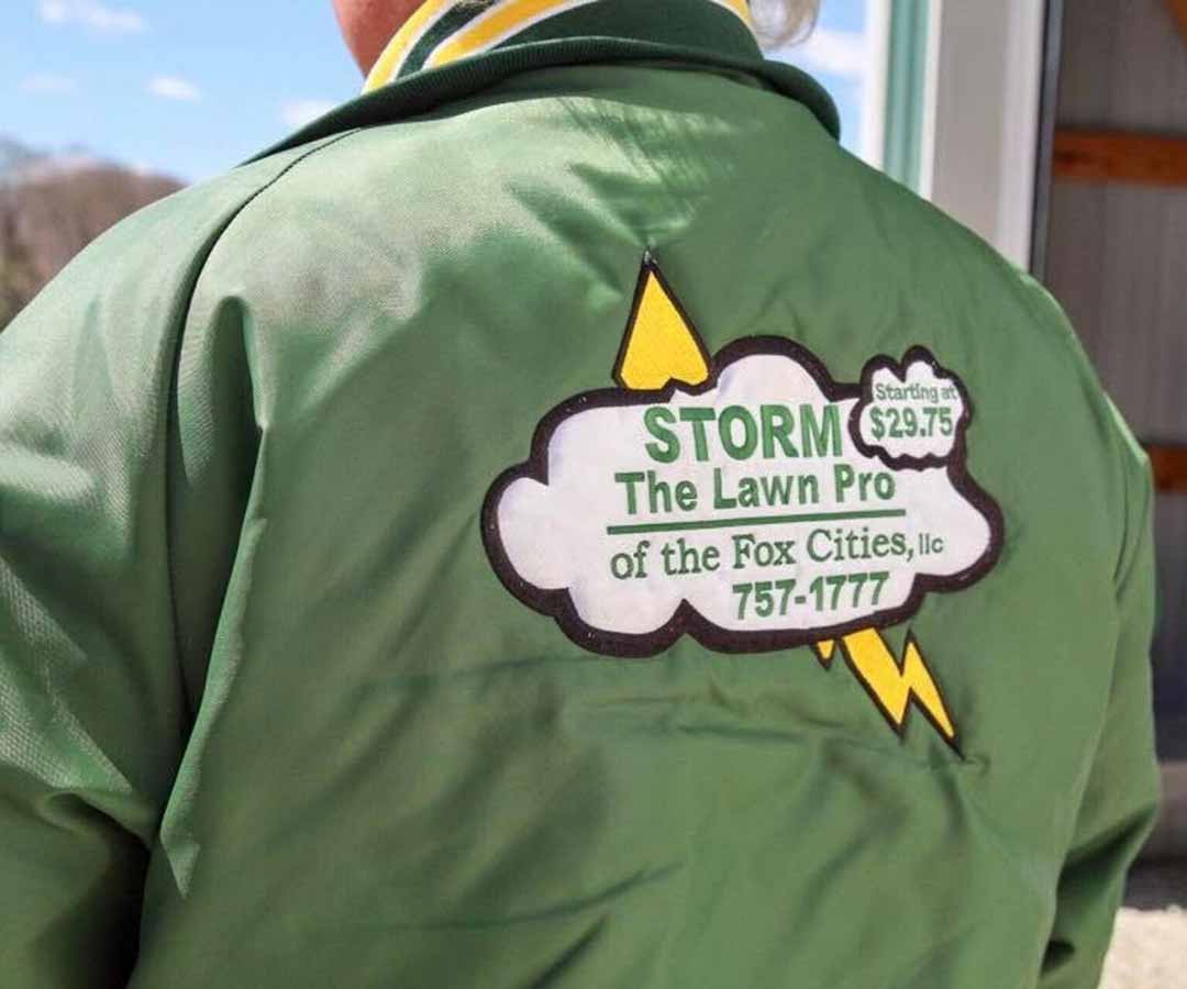 Logo patch on a green jacket of STORM - The Lawn Pro of The Fox Cities. 